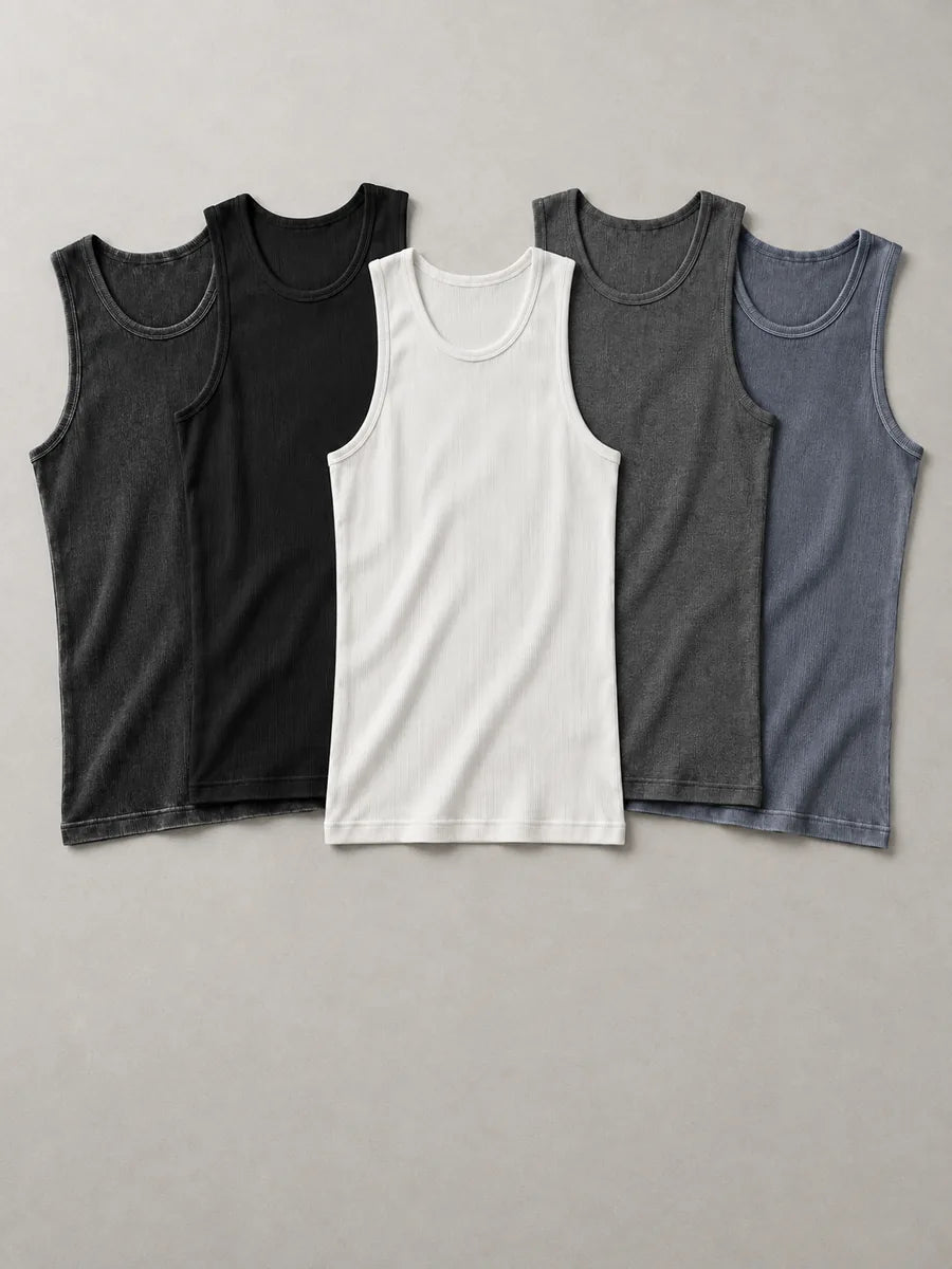 Fünf flach ausgelegte Tanktops: drei einfarbige in Schwarz, Weiß und Anthrazit, zwei im Washed-Look in Schwarz und Stahlblau
