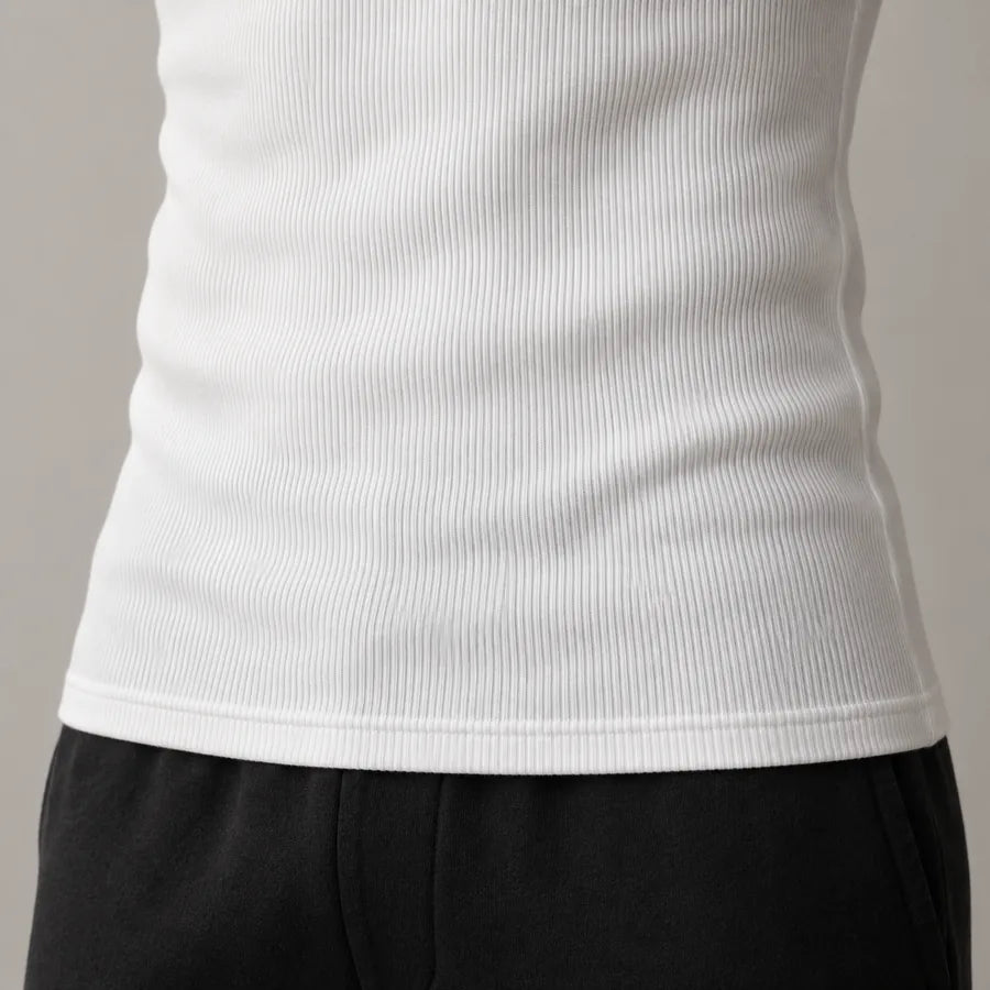 Saum eines getragenen weißen Ripp-Tanktops, der gerade und flach auf dem Bund einer schwarzen Hose liegt